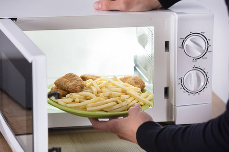 s Hand Putting Fried Food Inside Microwave Oven