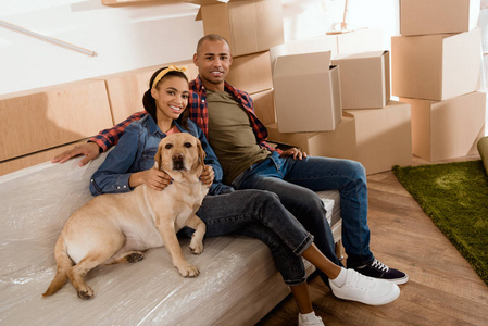 非裔美国人夫妇带着拉布拉多犬在新家沙发上休息