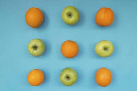 蓝色背景下新鲜橙子和苹果五颜六色的水果图案的顶部视图