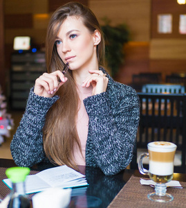 年轻漂亮的女人坐在咖啡桌和喝咖啡而工作