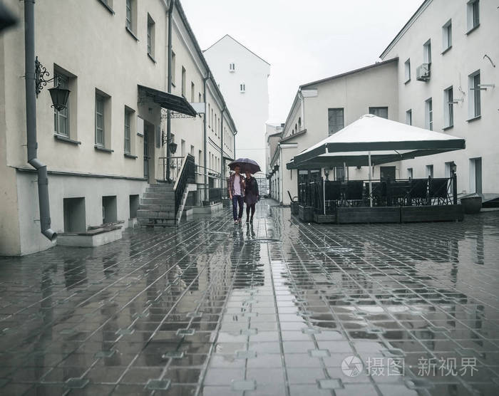 在雨天幸福的情侣在城市街道的伞下