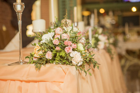 婚礼桌装饰充满玫瑰和Eustoma花，蜡烛和桃色织物。豪华丰富的餐厅内部。室内。复制空间