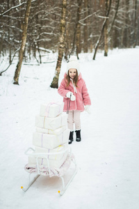 女孩拿着一个带礼品盒的雪橇