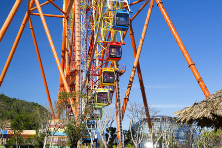 传统的亚洲建筑背景上的一个巨大的现代色彩鲜艳的摩天轮在一个游乐园的蓝天背景下