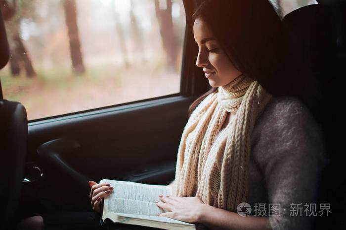 女人在车里秋天的概念微笑俏丽的女孩读书移动在汽车
