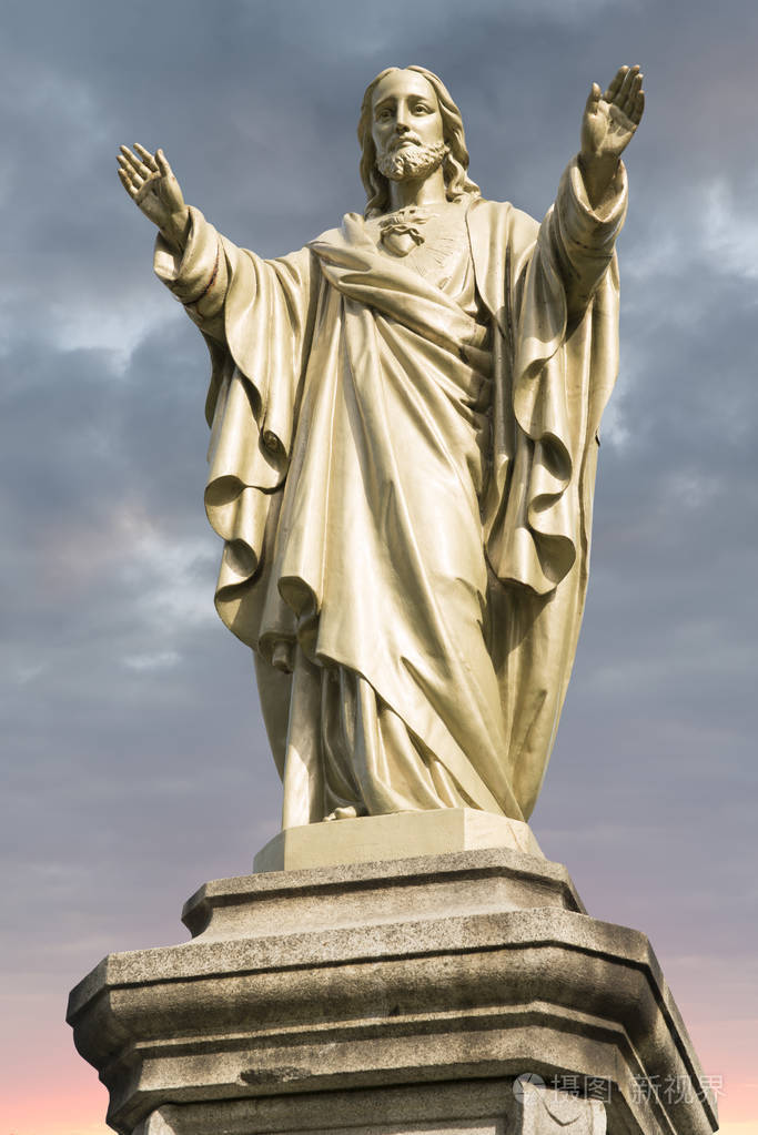 耶稣基督雕像背景是多云的天空和日出