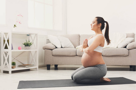 快乐怀孕的妇女训练瑜伽在英雄姿势