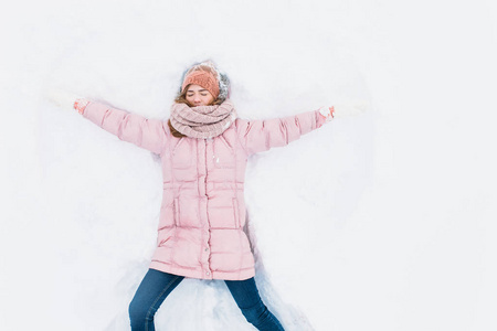 快乐的女人躺在雪地里, 胳膊和腿上下移动, 创造了一个雪天使的形状。微笑的妇女躺在雪地上的寒假, 为广告
