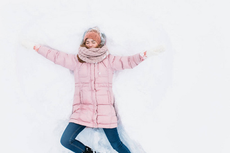快乐的女人躺在雪地里, 胳膊和腿上下移动, 创造了一个雪天使的形状。微笑的妇女躺在雪地上的寒假, 为广告