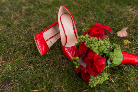 s bouquet of red roses and green berries on green grass backgrou