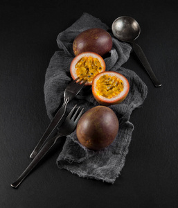 餐巾纸和石板桌上的新鲜成熟的激情水果可以作为背景