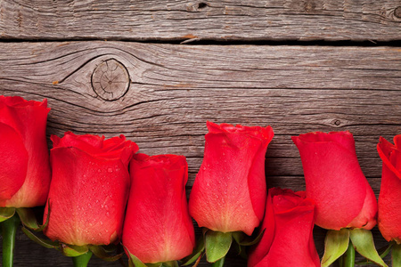 情人节贺卡上有红色玫瑰放在木桌上。 带空间的顶景，您的问候