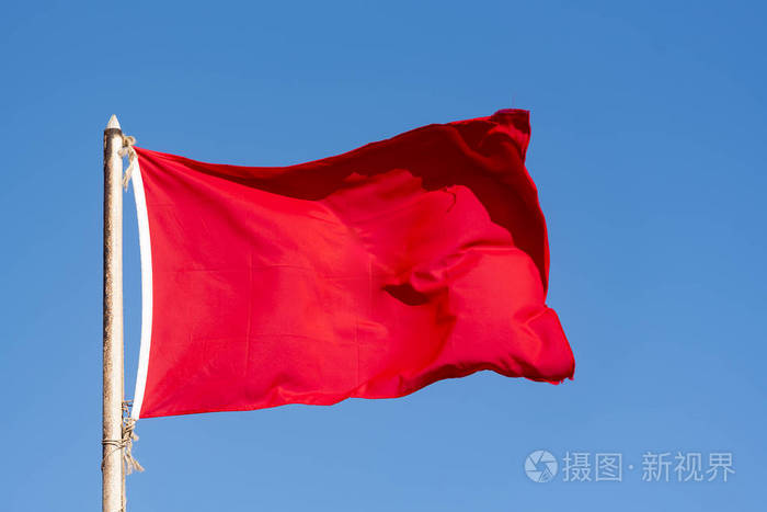 古老的红旗和蓝天的红旗在蓝天上飘扬