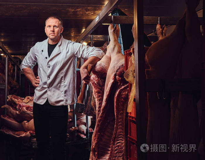 穿着白色厨房长袍的屠夫在一家肉类冷藏厂工作.