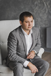 一个穿着灰色西装的年轻男子坐在灰色模式的沙发上