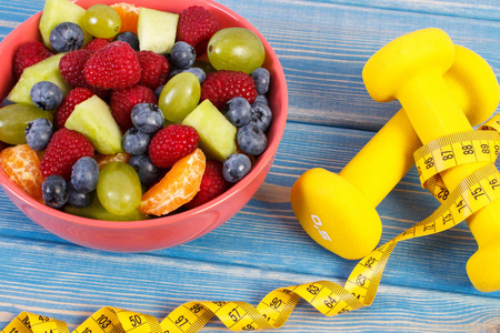 新鲜的水果沙拉和厘米的哑铃, 健康的生活方式和营养概念