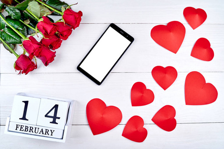 情人节背景与红色玫瑰花束手机与空白屏幕纸心和2月14日木块日历复制空间。 贺卡模型。 爱的概念。 俯视图平躺