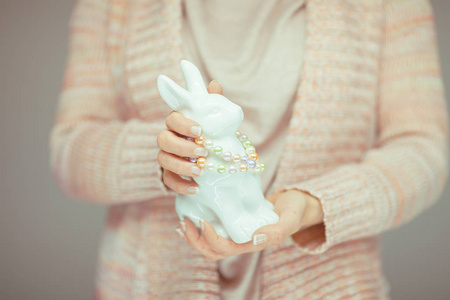 女人手里拿着复活节兔子，手里拿着浅粉红色的粉彩可以作为浪漫的背景