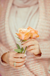女人手里拿着玫瑰花，手里拿着淡粉色的粉彩可以作为浪漫的背景