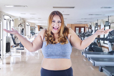 肥胖妇女在健身房中心看起来很开心