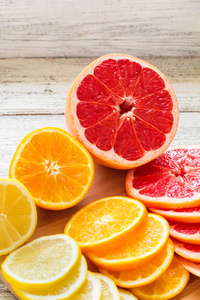切片新鲜柑橘柠檬葡萄水果橙子在木切割板上用刀。