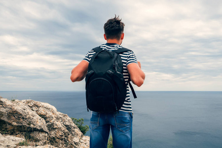 背上背着背包望海的男性旅行者