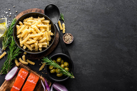 意大利面鲑鱼鱼和配料烹饪在黑色背景顶部视图。 意大利食品