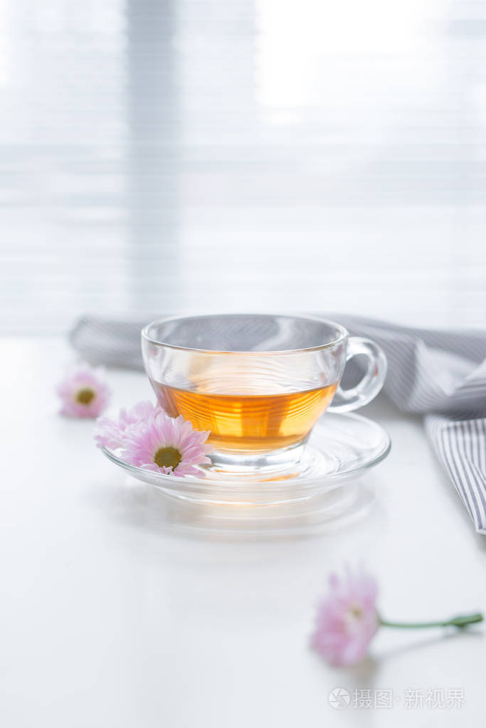 玻璃杯茶和窗台上的粉红色花关闭