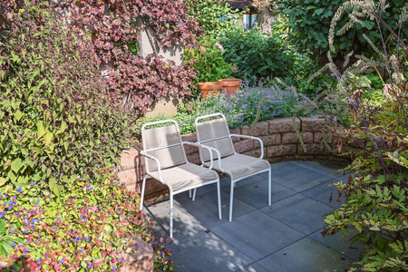 在美丽的秋天花园的角落里坐两把椅子享受阳光