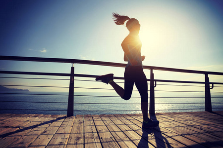 运动健身女跑步者日出时在海滨木板路上跑步照片