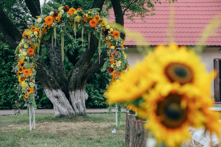 带有向日葵和木制装饰品的婚礼用花式乡村拱门