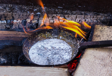 用熔融金属铝铅制备的容器煎锅在橙色火焰背景下铸造