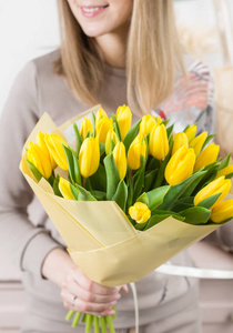 美丽的豪华花束在女性手中的黄色郁金香花。花店的花匠的工作。可爱可爱的女孩