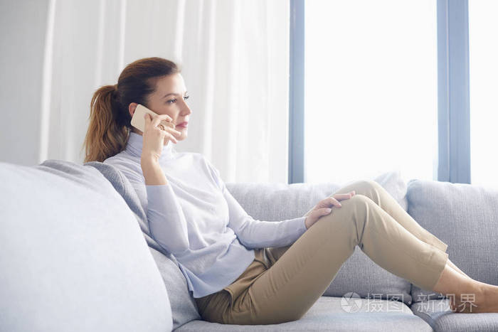 有吸引力的成熟女人在家里放松时使用手机和打电话.