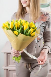美丽的豪华花束在女性手中的黄色郁金香花。花店的花匠的工作。可爱可爱的女孩