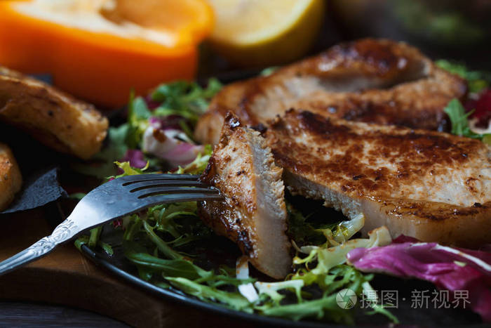 炸肉, 一块牛排放在叉子上, 用沙拉香草胡椒柠檬和面包在深色的木制背景下。明信片的背景