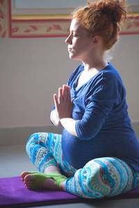红头怀孕的年轻女子在瑜伽课上冥想