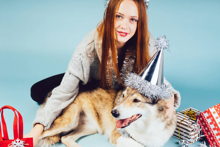 快乐的女人在圣诞帽旁边坐在狗的礼物背景