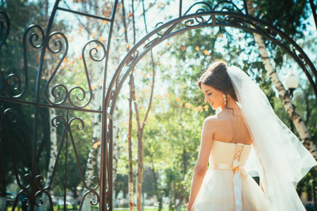 年轻美丽的新娘站在公园凉亭图片