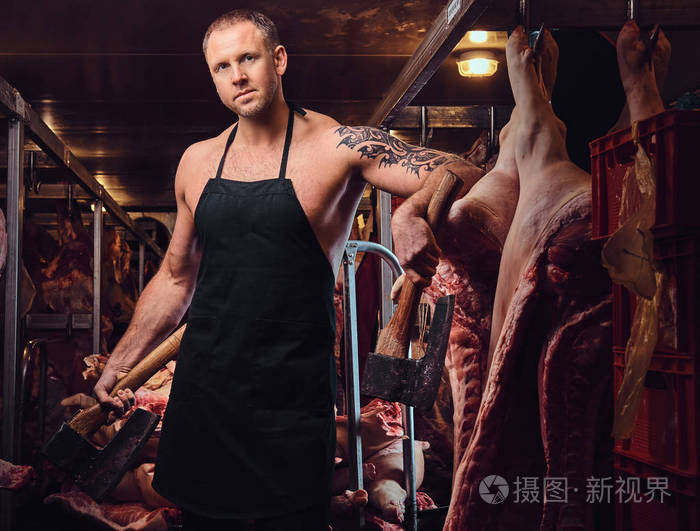 一个穿围裙的屠夫的肖像在肉厂里拿着一把斧头