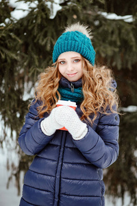 冬天在公园或树林里散步。 那个年轻漂亮的女孩，穿着温暖的帽子和一件羽绒垫外套的蓝色眼睛的金发女孩，用雪花手套抓住了一只手。 有降