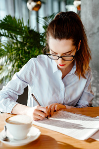 s portrait in  shirt and strict glasses. the woman sits at