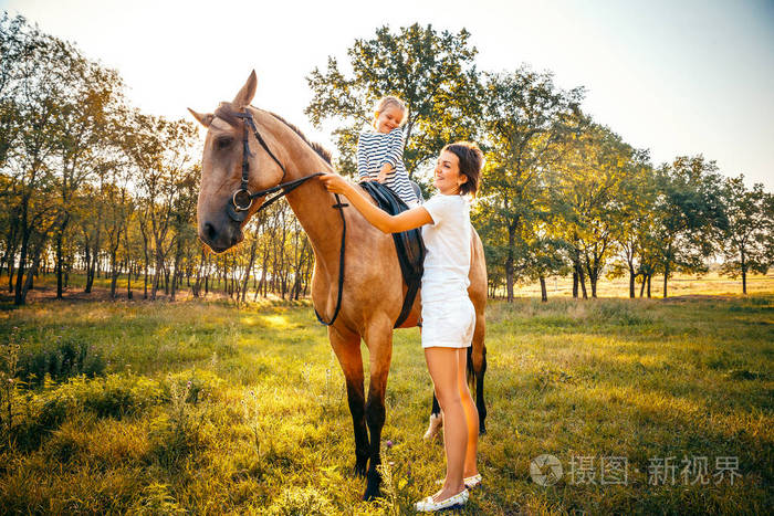小女孩骑马与她的母亲站在 nearb