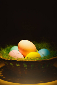 彩色粉彩声道传统彩绘复活节彩蛋篮子与绿草在黑暗的黄色背景与黑色的阴影, 剪影, 光。广告的复制空间。与地方为文本