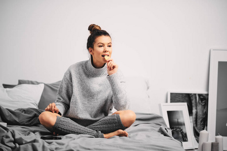 女人坐在床上吃饼干的肖像