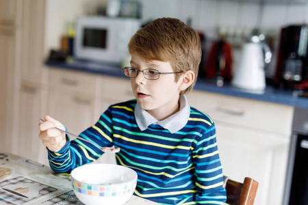 快乐小金发孩子男孩吃谷类早餐或午餐。儿童的健康饮食
