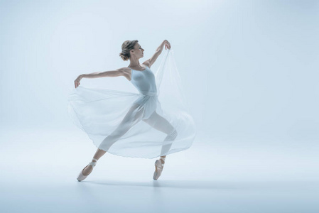 优雅的芭蕾舞女演员，穿着白色连衣裙在工作室跳舞，与白色隔离