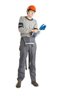 一个年轻的男子在工作灰色的衣服和橙色安全帽戴上手套的白色隔离背景