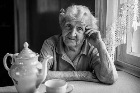 餐桌上喝茶的老妇人的肖像。