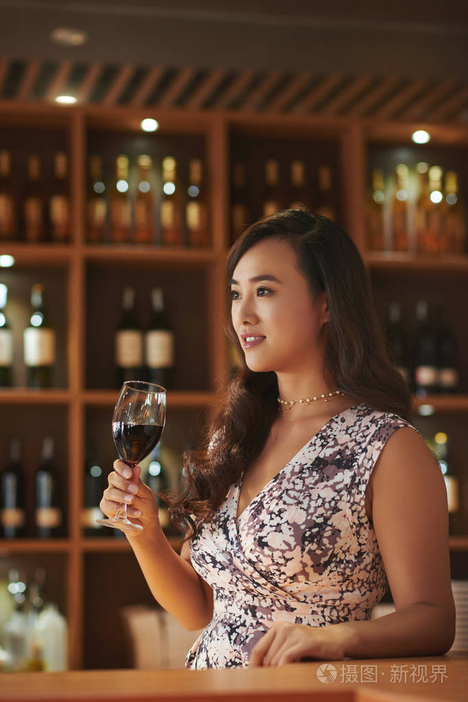 年轻的亚洲女人品尝红酒